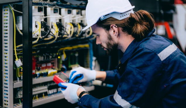 Professional technician checking and repairing part of automatic machine at industrial factory